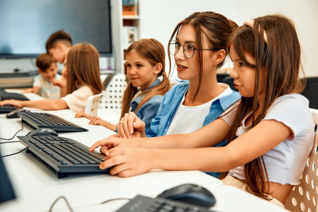 Children and a teacher in front of computers